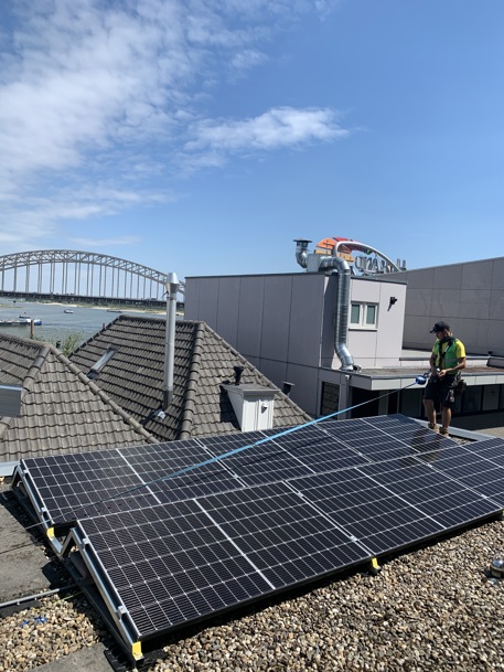 Tegen de fraaie achtergrond van de Waalbrug plaatsten monteurs van Ecorus zonnepanelen op de appartementencomplexen van Portaal in de Vleeshouwerstraat in Nijmegen.